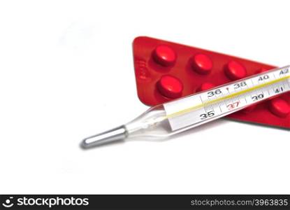 Thermometer and tablets on white background
