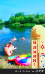 thermometer with indication 31 degrees and bathing people. thermometer with indication 31 degrees and bathing people. People swim in the river in hot summer