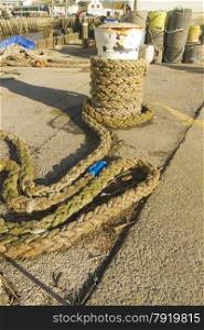 Thick Rope partially wound around ship?s mooring bollard, West Bay, Bridport, England, United Kingdom, Europe.