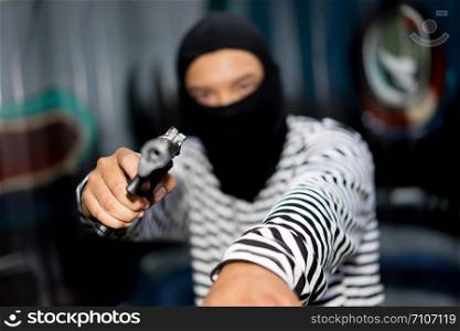 Thief holding gun aiming pistol in hand ready to shoot. The criminal robber or gangster thief concept
