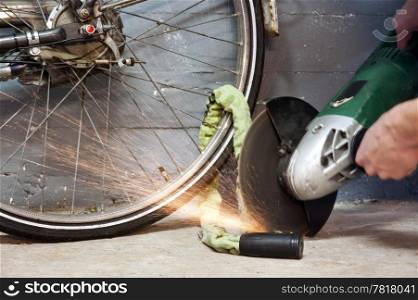 Thief opening the lock of a bicycle with a portable grinding machine