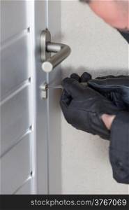 Thief with a bar of iron in the hand to open a door