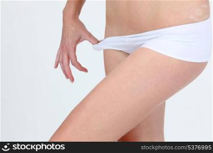 thin naked woman pulling her pants