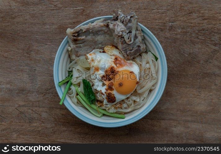 Thin rice noodles soup with Pork ribs, Fried egg and vegetable sprinkle with smoked shrimp paste chili dip serving in ceramic bowl. Asia style food, Top view, Selective focus.
