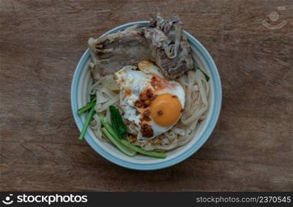 Thin rice noodles soup with Pork ribs, Fried egg and vegetable sprinkle with smoked shrimp paste chili dip serving in ceramic bowl. Asia style food, Top view, Selective focus.