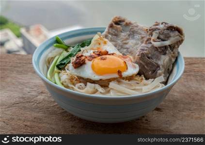 Thin rice noodles soup with Pork ribs, Fried egg and vegetable sprinkle with smoked shrimp paste chili dip serving in ceramic bowl. Asia style food, Selective focus.