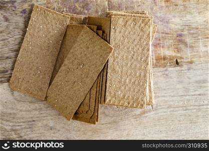 Thin rye crispy crackers lying on a wooden cutting board in the kitchen, Food Rich in fiber. Thin rye crispy crackers