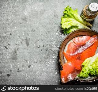 Thin slices of salted salmon with herbs and salt. On a stone background.. Thin slices of salted salmon with herbs and salt.