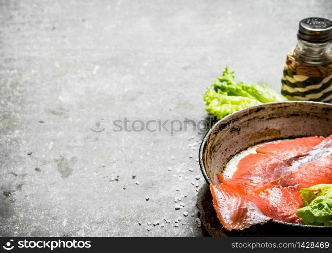 Thin slices of salted salmon with herbs and salt. On a stone background.. Thin slices of salted salmon with herbs and salt.