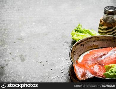 Thin slices of salted salmon with herbs and salt. On a stone background.. Thin slices of salted salmon with herbs and salt.