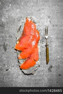 Thin slices of smoked salmon with a fork. On a stone background.. Thin slices of smoked salmon with a fork.
