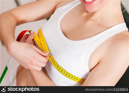 Thin woman measuring her chest with a tape measure, only the torso to be seen