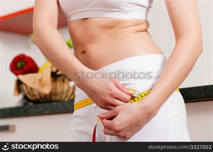 Thin woman measuring her hip with a tape measure, only the torso to be seen