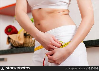 Thin woman measuring her hip with a tape measure, only the torso to be seen