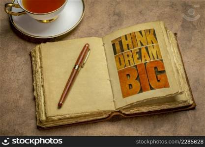 think and dream big motivational phrase - word abstract in letterpress wood type printing blocks in a retro journal with a cup of tea