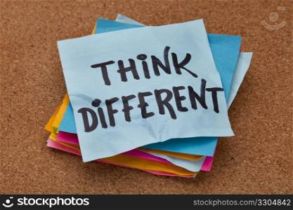 think different concept - motivational phrase on a stack of sticky notes against cork bulletin board