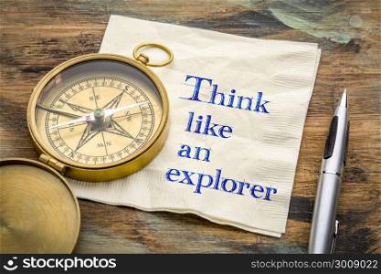 Think like an explorer - inspiraitonal handwriting on a napkin with an antique brass compass