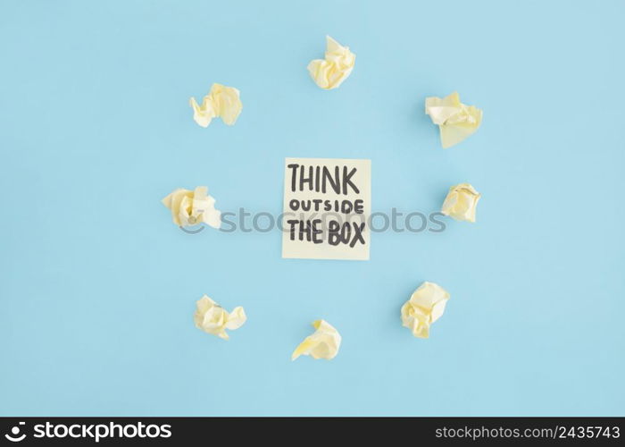 think outside box text adhesive note surrounded with yellow crumpled paper blue backdrop