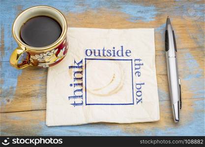 Think outside the box concept - hadwiting on a napkin with a cup of coffee