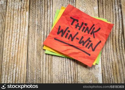 Think win-win concept - handwriting on a sticky note against grunge wood board