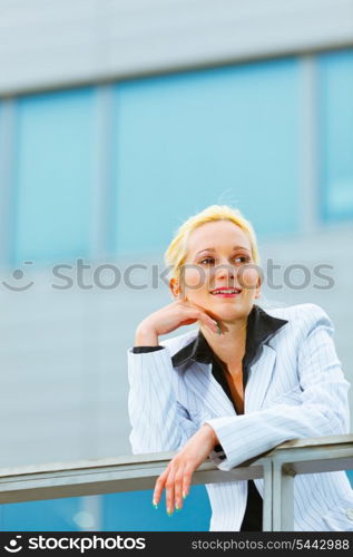 Thinking about something modern business woman leaning on railing at office building &#xA;