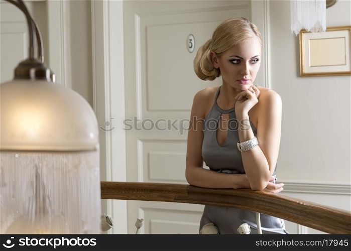thinking beautiful woman near a door , with hair style and elegant dress . she is looking on one side