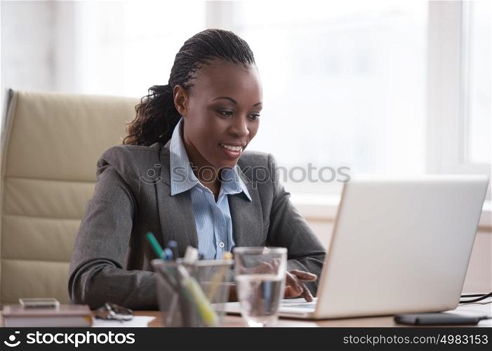 Thinking businesswoman in suit sitting at workplace and working hard with laptop