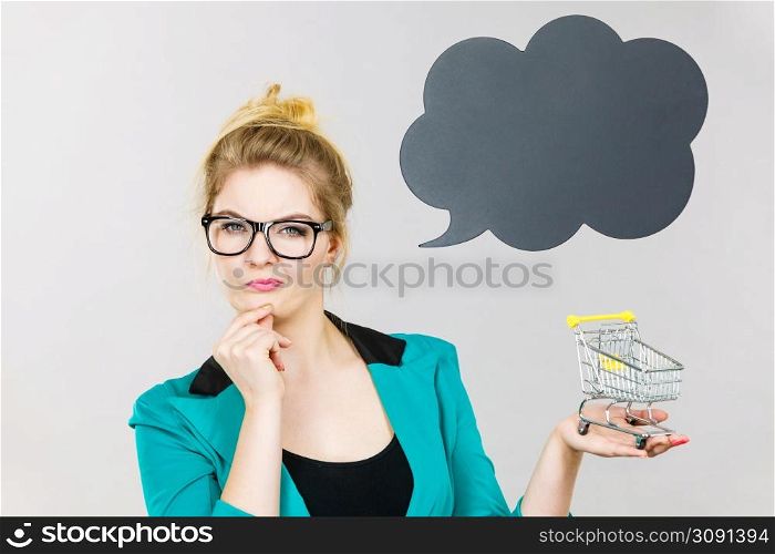 Thinking buying things at market shops concept. Business woman hand holding small tiny shopping cart trolley. Thinking business woman holding small tiny shopping cart
