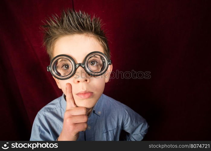 Thinking child with big glasses. Red curtain background