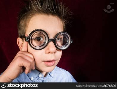 Thinking child with big glasses. Red curtain background