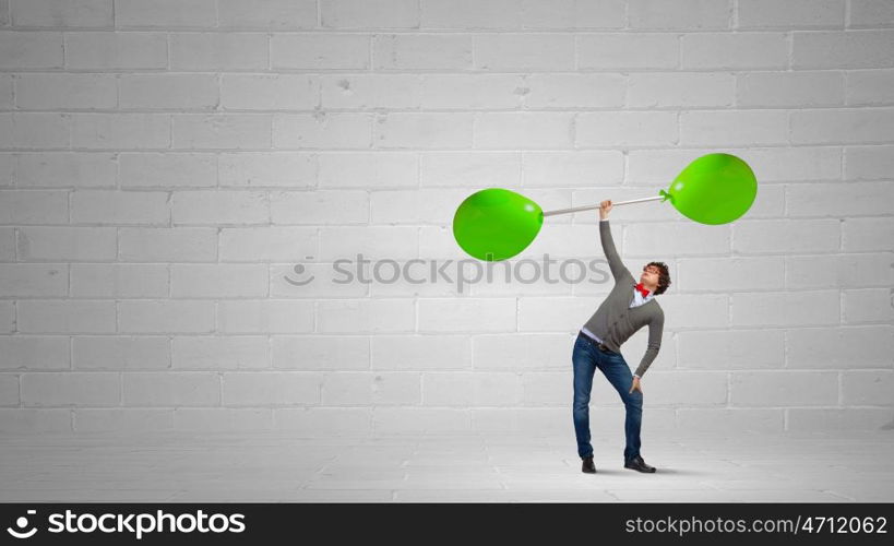 Thinking he is strong. Confident businessman lifting above head barbell with balloons