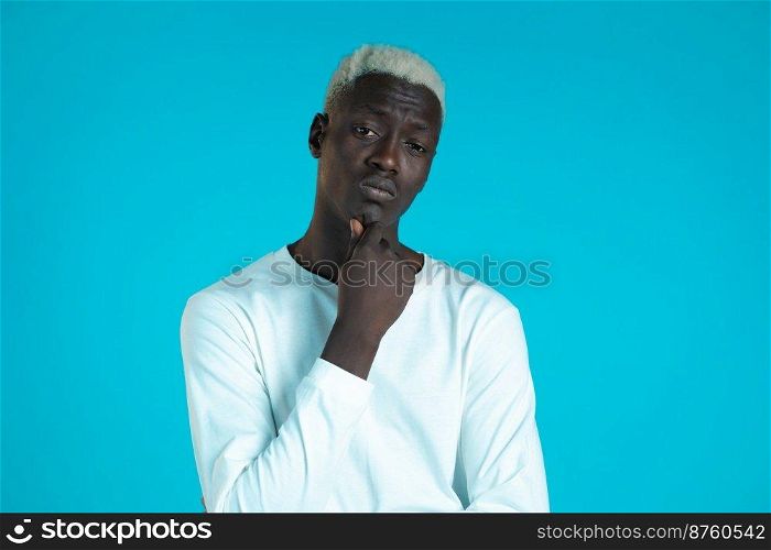 Thinking hipster african man looking up and around on blue background. Pensive face expressions. Handsome male black model. Thinking hipster african man looking up and around on blue background. Pensive face expressions. Handsome male black model.