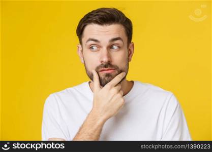 Thinking man isolated on yellow background. Closeup portrait of a casual young pensive man looking up at copyspace. Caucasian male model. Thinking man isolated on yellow background. Closeup portrait of a casual young pensive man looking up at copyspace. Caucasian male model.