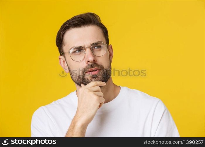 Thinking man isolated on yellow background. Closeup portrait of a casual young pensive man looking up at copyspace. Caucasian male model. Thinking man isolated on yellow background. Closeup portrait of a casual young pensive man looking up at copyspace. Caucasian male model.