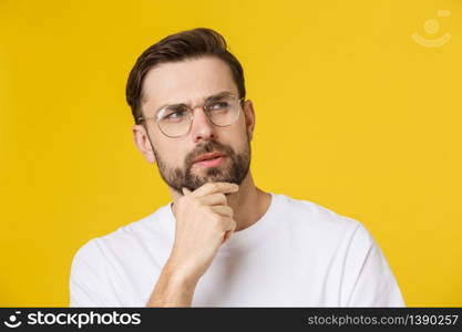 Thinking man isolated on yellow background. Closeup portrait of a casual young pensive man looking up at copyspace. Caucasian male model. Thinking man isolated on yellow background. Closeup portrait of a casual young pensive man looking up at copyspace. Caucasian male model.