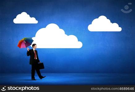 Thinking optimistic. Businessman walking with suitcase and with colorful umbrella