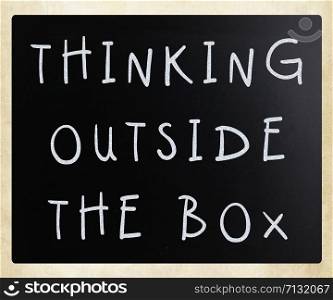 Thinking outside the box phrase, handwritten with white chalk on a blackboard