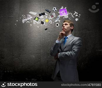Thinking over an idea. Young thoughtful businessman looking up with hand on chin