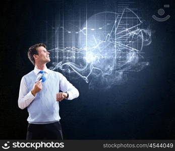 Thinking over the idea. Young businessman smoking pipe with diagrams and graphs at background