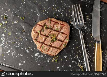 Thinly sliced grilled tenderloin on black stone cutting board