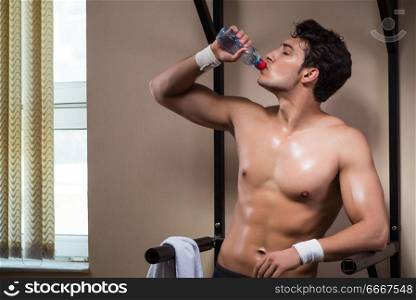 Thirsty man drinking water in sports gym