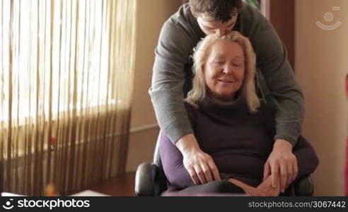 Thirty-year-old son hugs his mother looking to the camera.