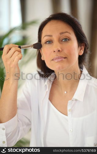 Thirty years old woman applying blush