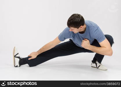 thirty young athletic man does physical exercises. Athlete crouching pulling muscles of the right leg