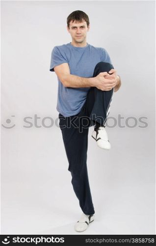 thirty young athletic man does physical exercises. Athlete flexing muscles of the legs