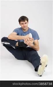 thirty young athletic man does physical exercises. Athlete flexing the foot of right leg