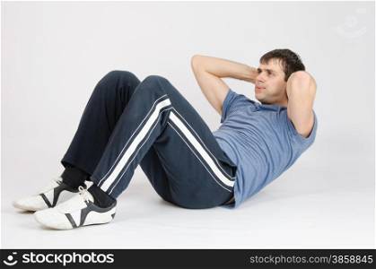 thirty young athletic man does physical exercises. Athlete pumps press the abdomen