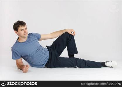 thirty young athletic man does physical exercises. Athlete resting reclining after complex of exercises