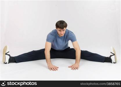 thirty young athletic man does physical exercises. Athlete sitting on the splits