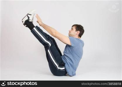 thirty young athletic man does physical exercises. Athlete stretching his arms raised to the feet